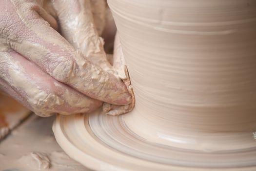 Hands of a potter, creating an earthen jar on the circle