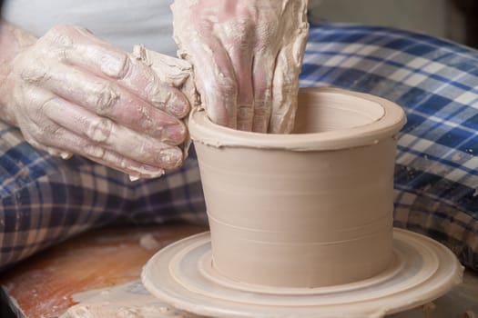 Hands of a potter, creating an earthen jar on the circle