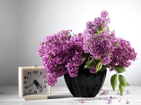 lilac flower on table with alarm clock