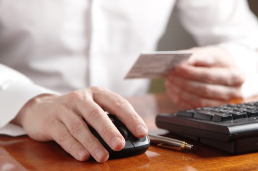 Hand of businessman on computer mouse next to the keyboard