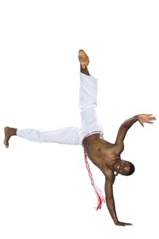 Capoeira, Brazilian Man standing on one hand, wearing white pants.