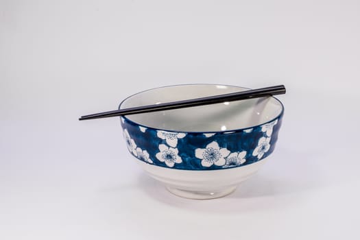 chinese ceramic bowel and black chopsticks on white scene,shallow focus