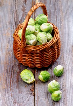 Fresh Raw Brussels Sprouts in Wicker Basket isolated on Rustic Wooden background