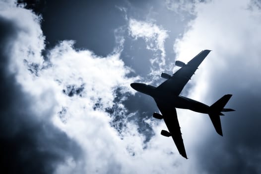 large passenger jet silhouette against a blue tinted sky