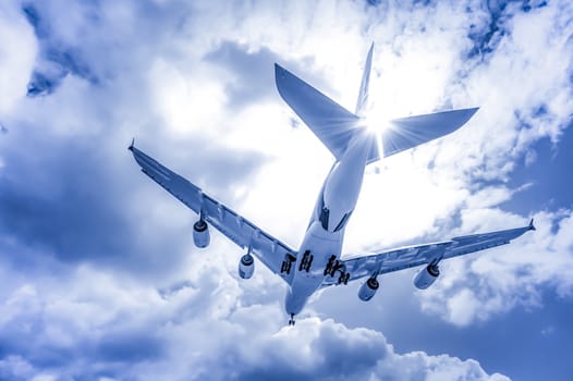 abstract of a large passenger jet landing through blue toned clouds