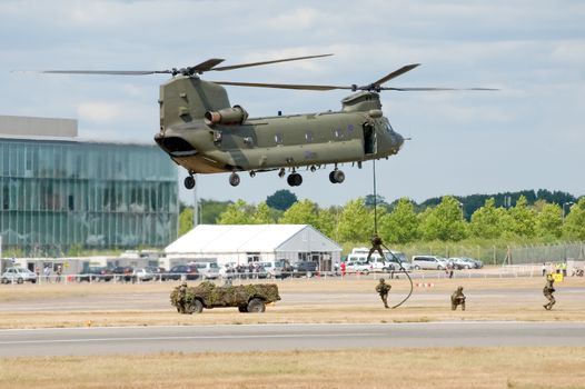 Farnborough, UK - July 24, 2010: RAF Chinook helicopter giving a vehicle and troop deployment demonstration at the Farnborough Airshow, UK