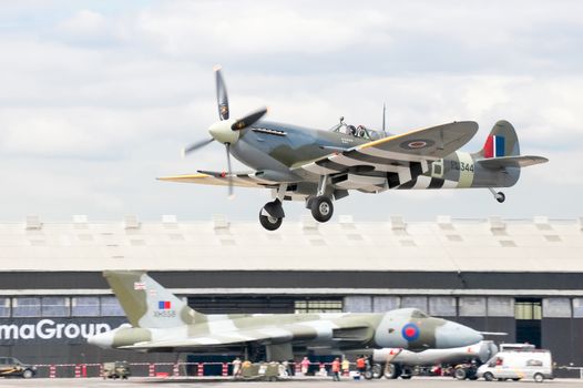 Farnborough, UK - July 24, 2010: WW2 Spitfire coming into land with XH558 Vulcan bomber in the background at the Farnborough Airshow, UK