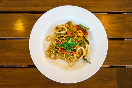 one dish of hot and spicy seafood spaghetti on wooden table,shallow focus