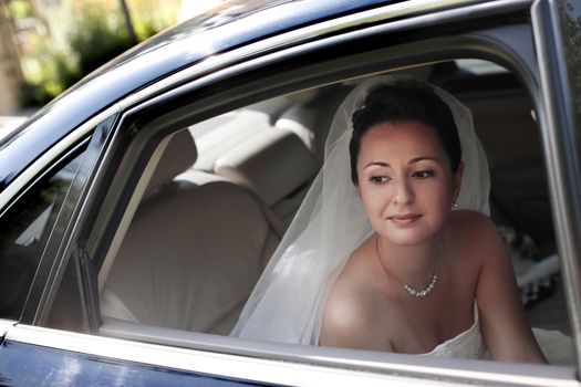The beautiful bride with bouquet in car