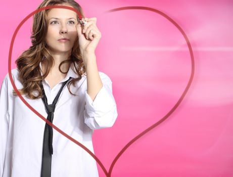 Woman painting lipstick heart on glass standing on a pink background