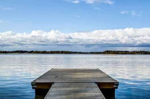 Pier under low clouds on a bright blue lake