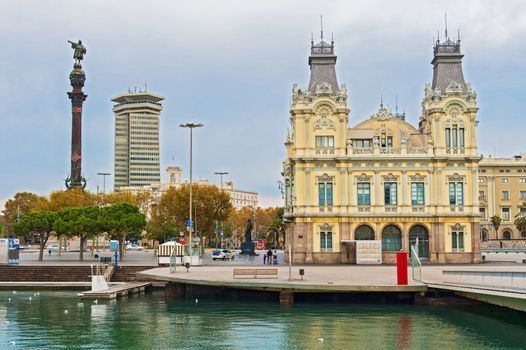 Barcelona, Spain - November 30, 2013: Port Authority building at Port Vell at the end of Las Ramblas.Tourists in square and Columbus monument on left  side.