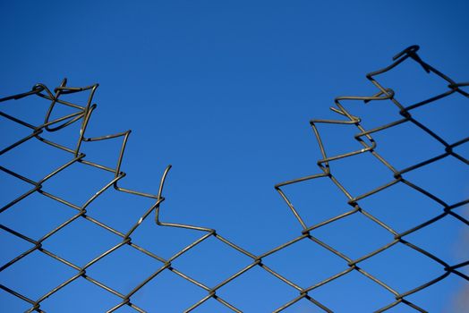 destroyed Steel net fence with blue sky background.