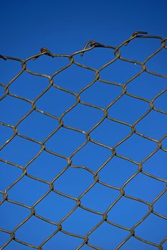 Steel net fence with blue sky background.