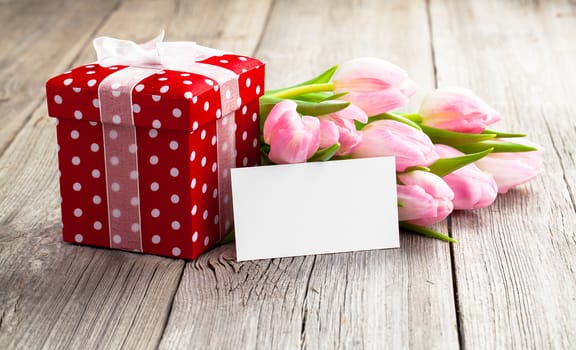 beautiful tulips with red polka-dot gift box. happy mothers day, romantic still life, fresh flowers. on wooden background