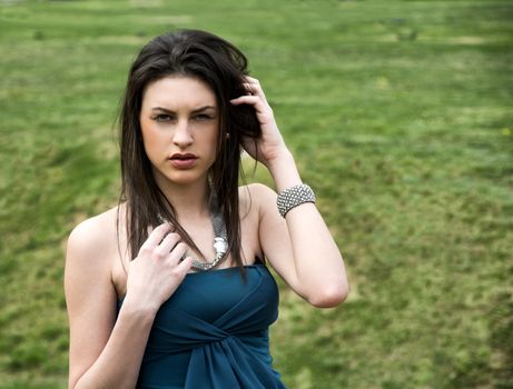 Attractive young woman in green grassland wearing elegant dress