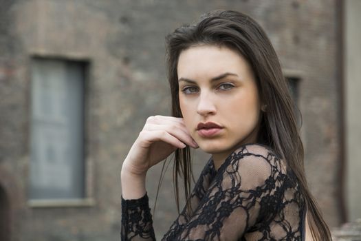 Profile of pretty brunette young woman outside, looking at camera