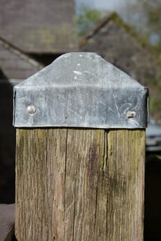 A lead post cap cut and folded protecting an oak wood post.