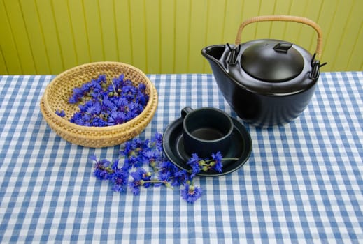 freshly picked cornflower on wicker basket and retro rustic clay tea set