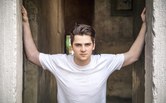 Young man with arms open on threshold, with confident look 
