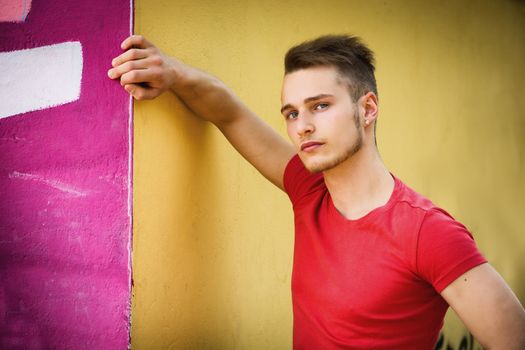 Attractive young blond man against colorful graffiti wall in red t-shirt