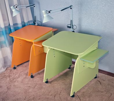 
Two home desks: light green and orange in the corner of a room at the blue wall on a brown carpet