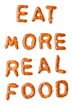 Slogan words EAT MORE REAL FOOD written, laid-out, with crispy alphabet pretzels isolated on white background