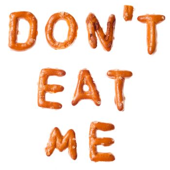 Words DONT EAT ME written, laid-out, with crispy alphabet pretzels isolated on white background