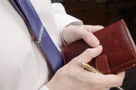 Businessman in white shirt holding leather wallet and pen