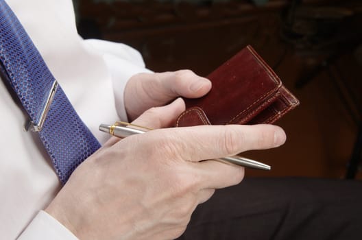 Businessman in white shirt holding leather wallet and pen