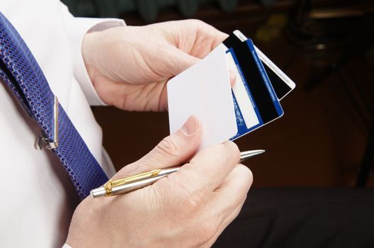 Businessman in white shirt holding credit cards and pen