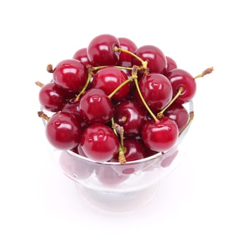 Ripe fresh cherry in the chrystal glass isolated on white background