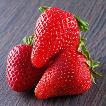 Some strawberries over a dark wooden table