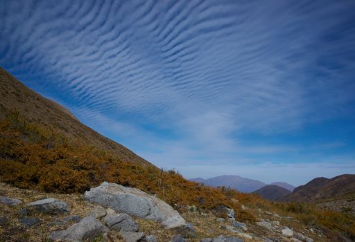 Intricate cloud formation above autumn coloured vegetation in the Yerba Loca Mountain Park near Santiago in Chile