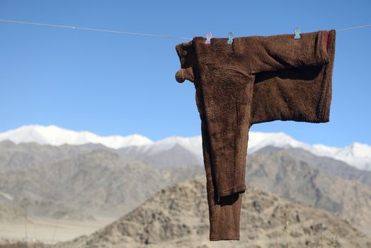 snow coats hanging to dry on wire in snow mountain background