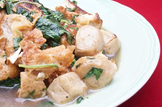 Basil Tofu Stir Fry and Vegetarian meatballs on dish with red background.