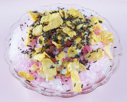 Shaved ice with syrup milk corn flakes and chocolate flakes.