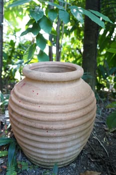 Jar made of clay is placed on the ground in the garden.