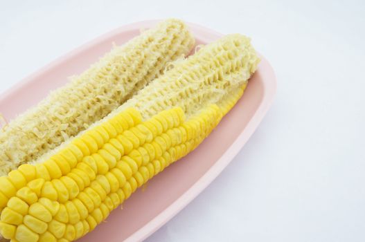 Corn eating and cob placed on pink trays with white background.