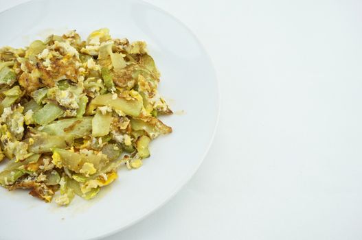 Chayote sliced fried with egg on white dish with white background.