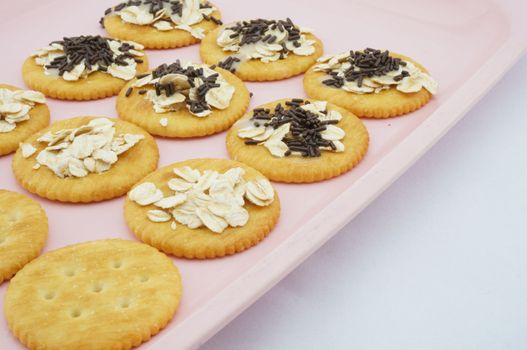 Crackers with oat, chocolate and  sweetened condensed milk placed on pink plate.