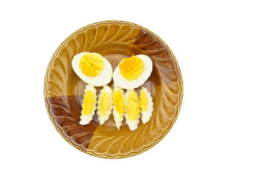 Boiled eggs cut in half and cut into small pieces place on a brown plate isolated with white background.