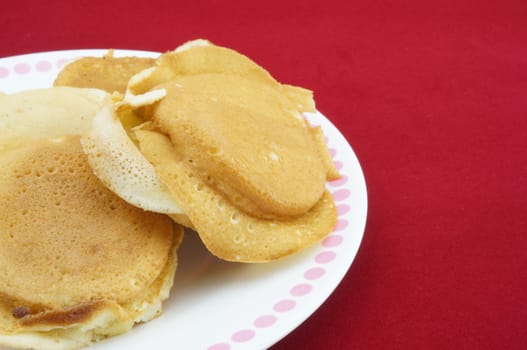 Appetizing yellow pancakes on white plate with red background. Make you hungry.