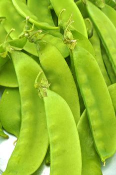 Green peas piled on a tray.As legumes, seeds and nuts are hatched inside.