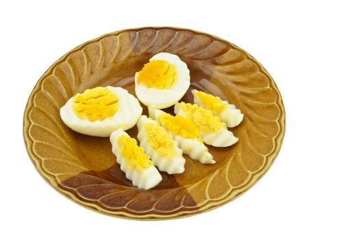 Boiled eggs cut in half and cut into small pieces place on a brown plate isolated with white background.