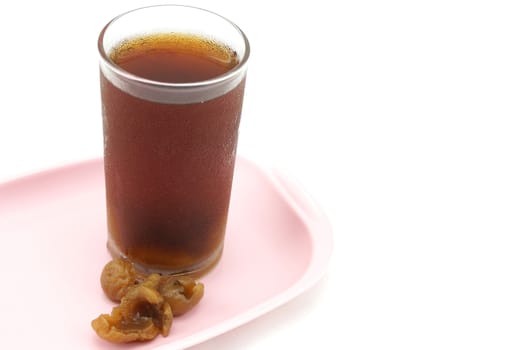 Longan juice into a glass and placed on a pink tray with white background.