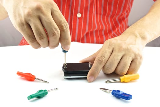 Man using screwdriver with screw for minor repair with white background.