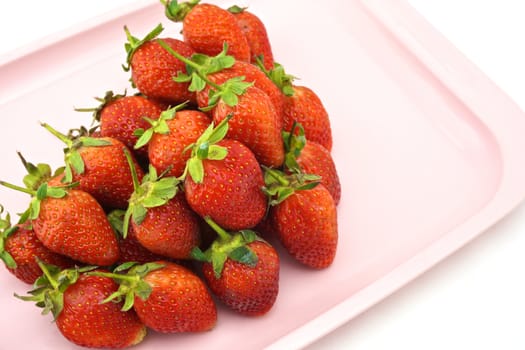 Red strawberry put a pile on a pink tray with white background.