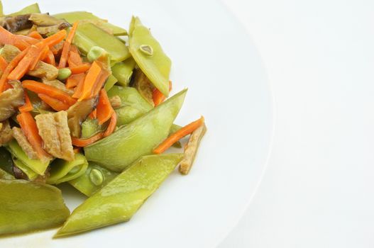 Green peas fried with carrot, mushroom and vegan protein on white dish with white background.