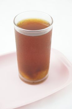 Longan juice into a glass and placed on a pink tray with white background.